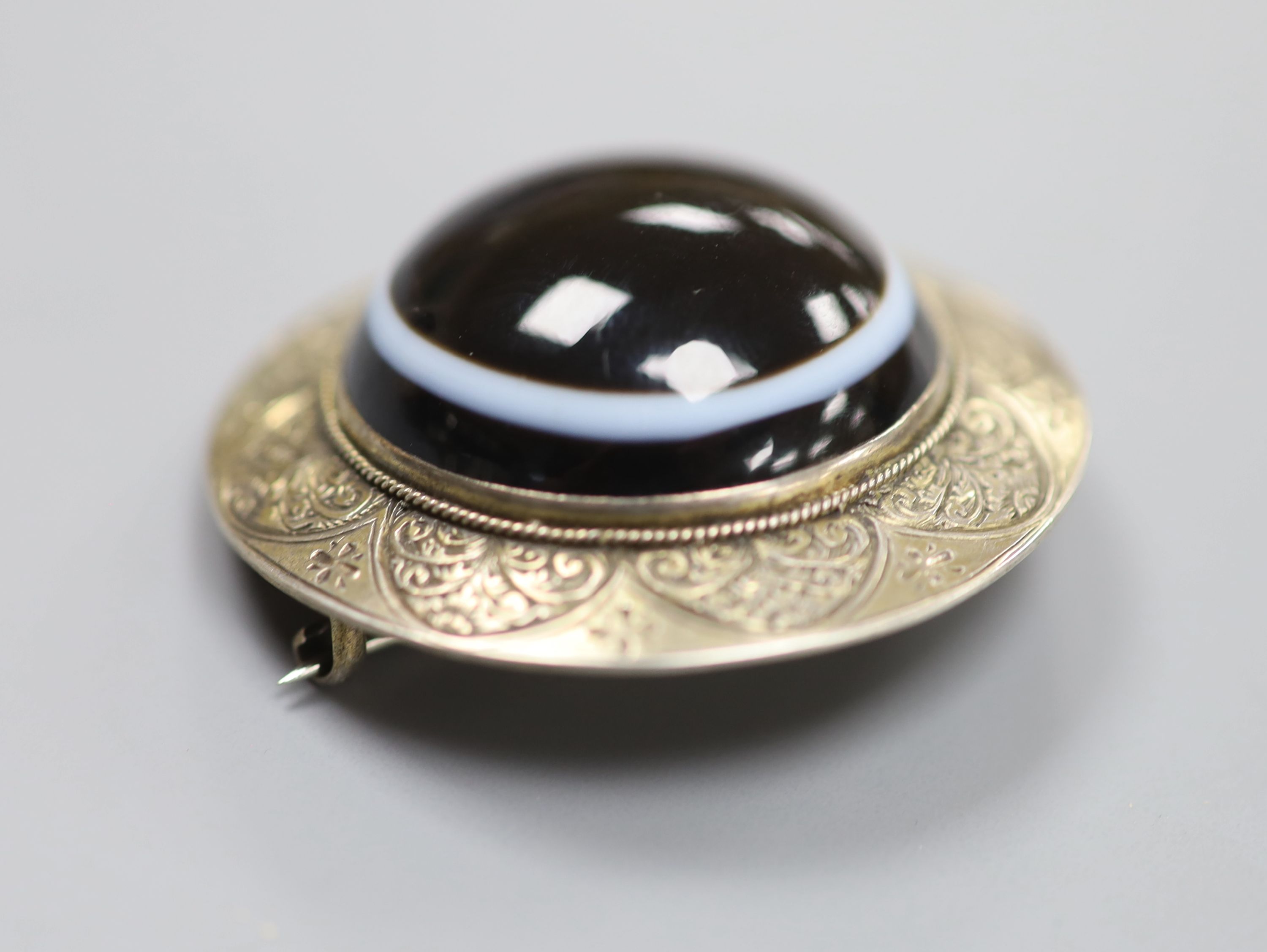 An engraved gilt white metal and banded agate set circular brooch